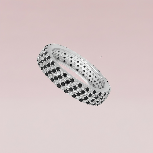 Silver ring with black and white gemstones on a pink background