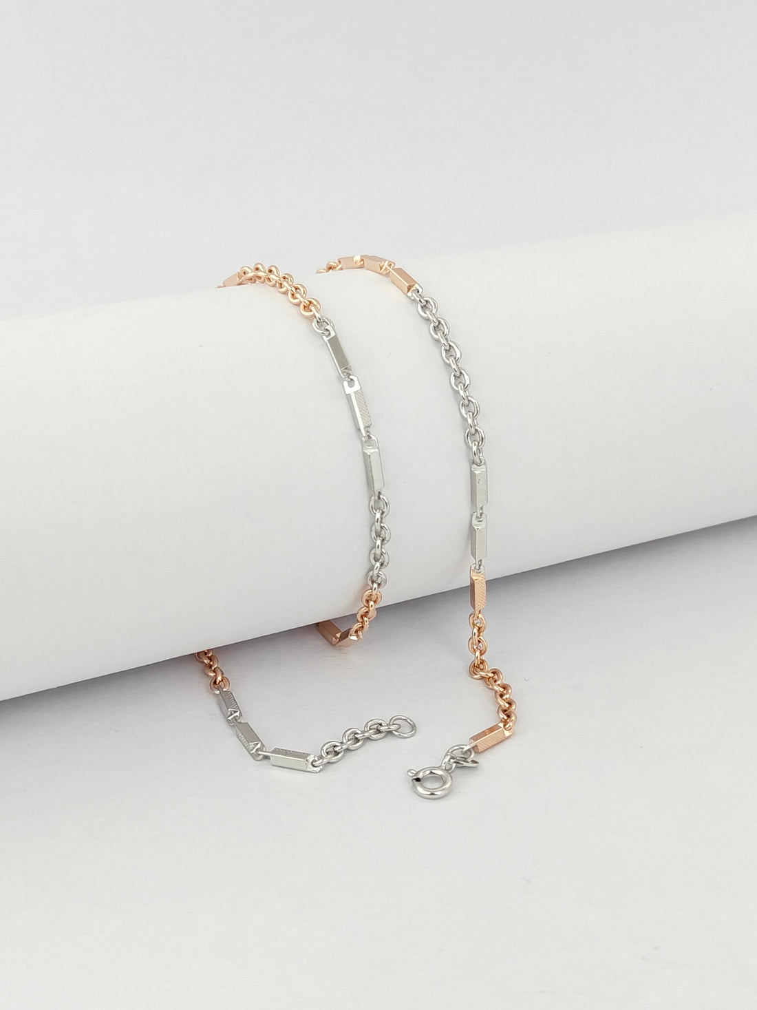 Two gold bracelets on a light gray surface