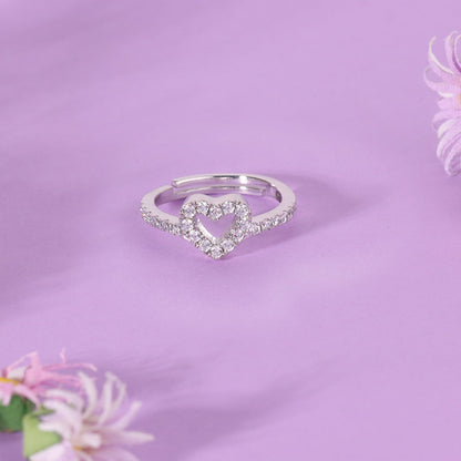 Silver heart-shaped ring on a purple background with flowers