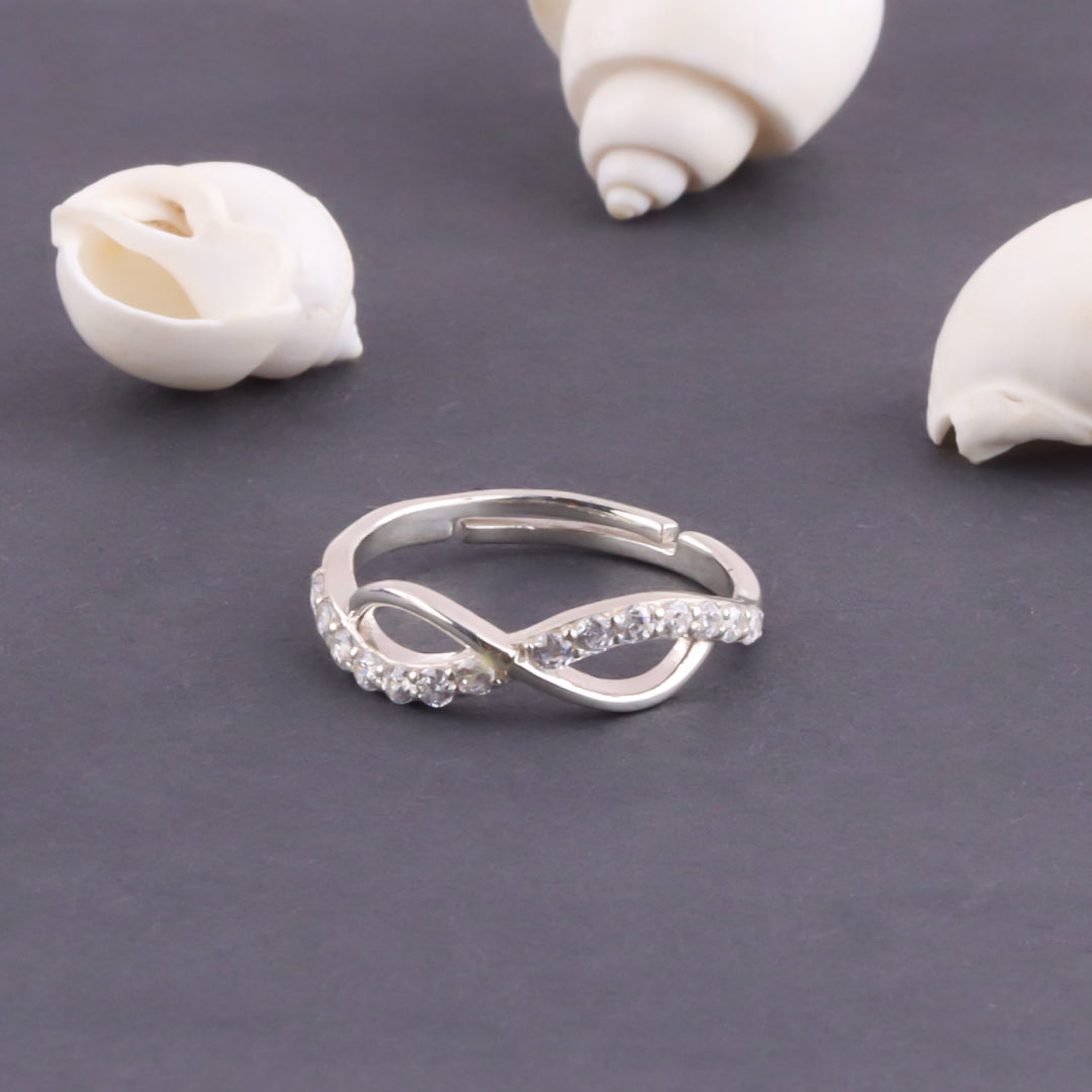 Silver ring with gemstones on a gray surface with shells