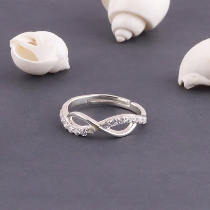 Silver ring with gemstones on a gray surface with shells